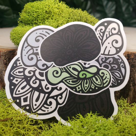 Sticker of green, cream, gray, and black hen of the woods mushrooms with stark black line art reminiscent of henna tattoo art. the sticker is sitting on moss and wood with ivy leaves in the background