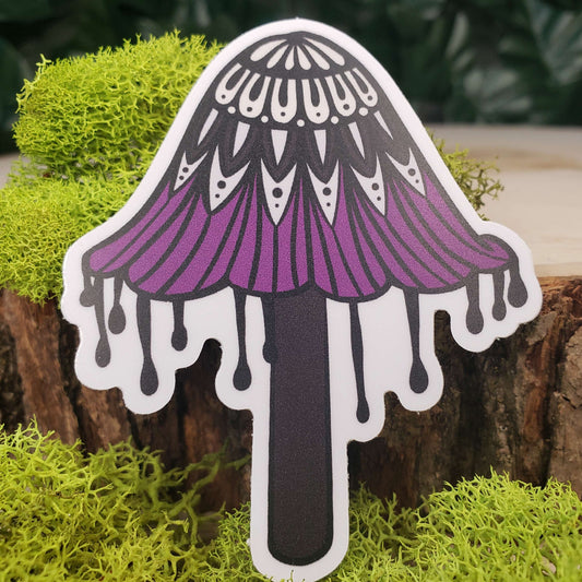 Sticker of a cream, light gray, purple, and black ink cap mushroom with stark black line art reminiscent of henna tattoo art. the sticker is sitting on moss and wood with ivy leaves in the background