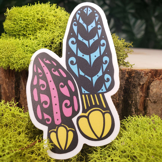Sticker of pink, blue, and yellow morel mushrooms with stark black line art reminiscent of henna tattoo art. the sticker is sitting on moss and wood with ivy leaves in the background